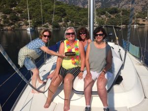 Four participants site on the deck of a yacht in Croatia with an island in the background