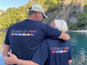Two participants embrace with their backs to the camera showing their Oceans of Hope flag t-shirts