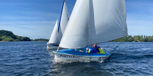 Two dinghies in full sail in a lake setting